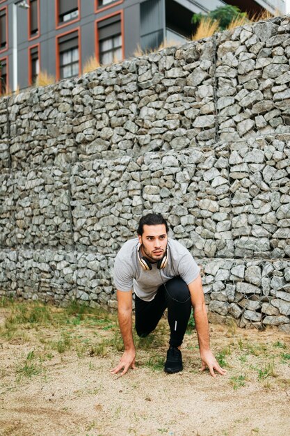 Городской спортсмен рядом с каменной стеной