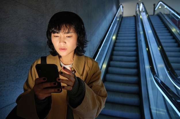 無料写真 都市のライフ スタイルとヘッドフォンで人々 の女性は彼女のスマート フォンのアプリでマップ publ をチェックで真剣に見えます