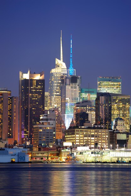 Urban modern architecture in New York City midtown Manhattan at dusk over river.