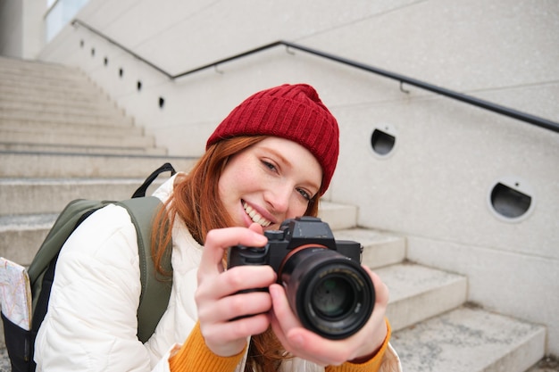 Urban people and lifestyle happy redhead woman takes photos holding professional digital camera phot