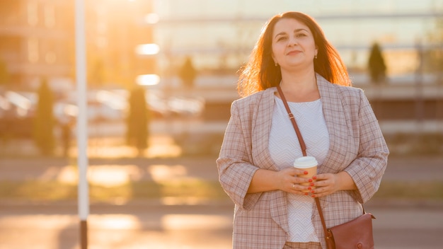 Urban portrait of smiley woman in costume at sunset with copy space