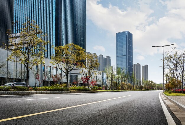 Urban road with green trees and skyscrapers