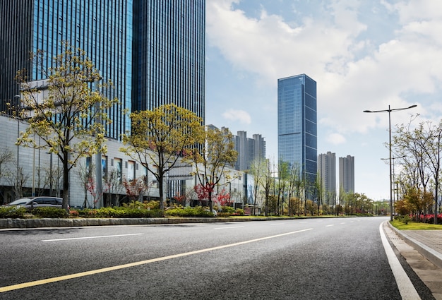 Urban road with green trees and skyscrapers