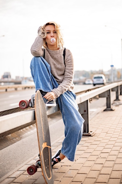 Urban stylish young girl walking with skateboard. Outdoors portrait of active sport woman model. Healthy lifestyle. Extreme sports. Fashion look, outdoor hipster portrait. Close up portrait of a prett