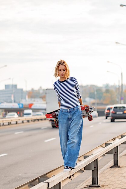 Urban stylish young girl walking with skateboard. Outdoors portrait of active sport woman model. Healthy lifestyle. Extreme sports. Fashion look, outdoor hipster portrait. Close up portrait of a prett