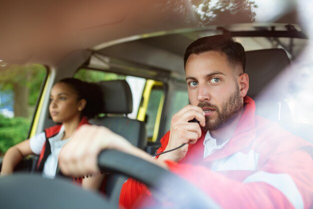 Urgent situation Two young paramedics in ambulance Male caucasian paramedic driving and talking over the radio