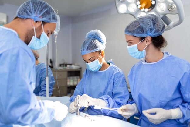 Urgent surgery Professional smart intelligent surgeons standing near the patient and performing an operation while saving his life