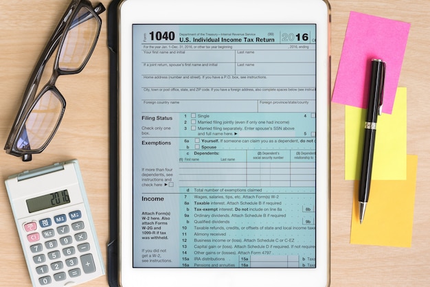 Налоговая форма США 1040 в таблетке с калькулятором и ручкой