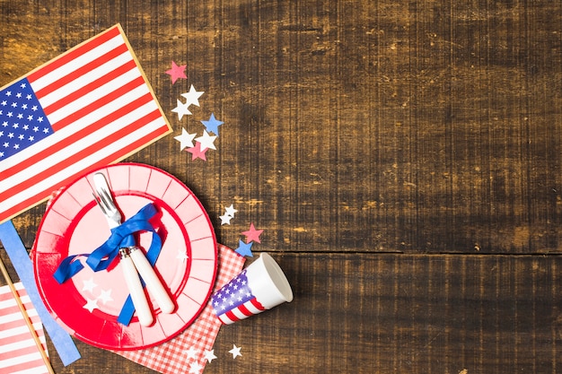 Free photo usa flag plate and cutlery tied with blue ribbon with flag; star and disposable cup on wooden desk