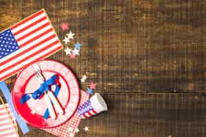 Free photo usa flag plate and cutlery tied with blue ribbon with flag; star and disposable cup on wooden desk