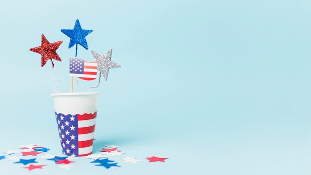 Usa flag and star props in the disposable cup against blue background