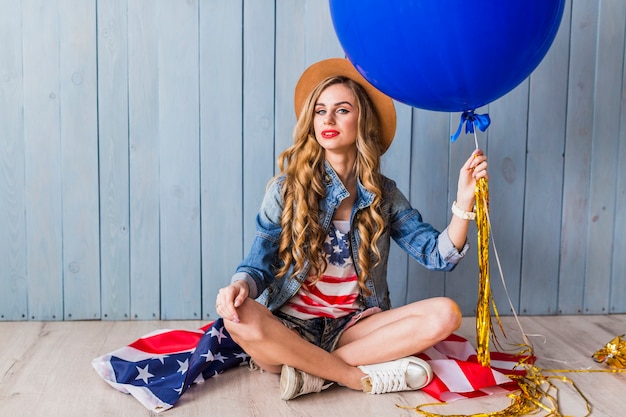 Concetto di festa dell'indipendenza degli stati uniti con la donna seduta e palloncino blu