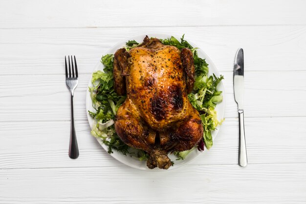 Utensils near chicken on salad