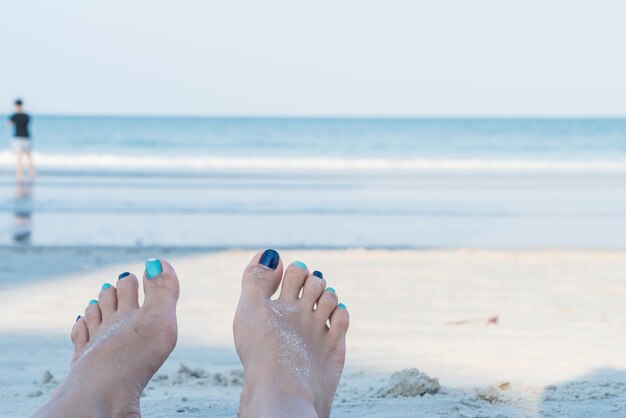 Vacation holidays. Woman feet closeup of girl relaxing on beach