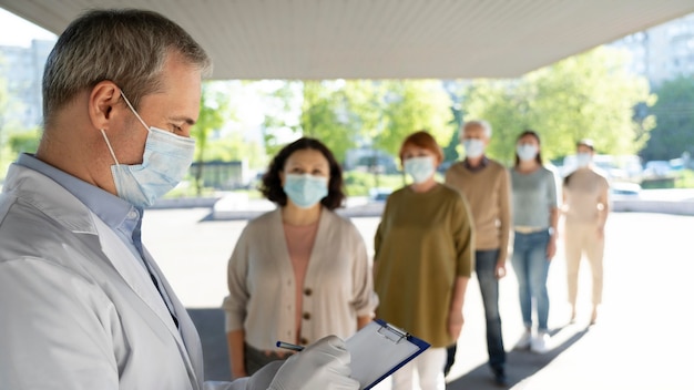 Medico di vaccinazione al centro che riempie le informazioni sui pazienti sul blocco note