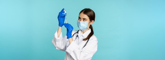 Covidとヘルスケアの概念からの予防接種フェイスマスクと手袋を使用した若い女性医師看護師