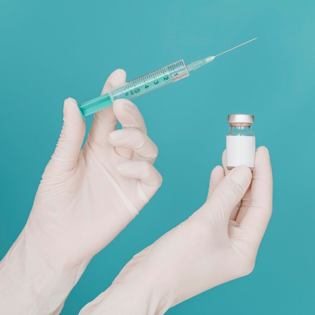 Vaccine bottle and syringe held by hands with gloves