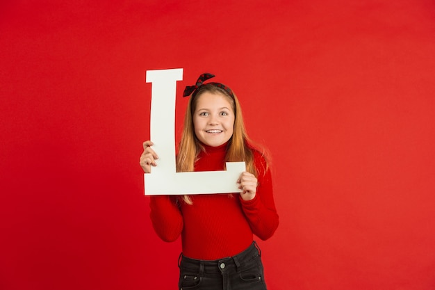 バレンタインデー​の​お祝い​、​赤い​背景​の​上​の​手紙​を​保持している​幸せな​白人​の​女の子