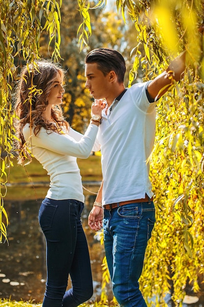 Valentine's day. Young couple posing under green-yellow tree.