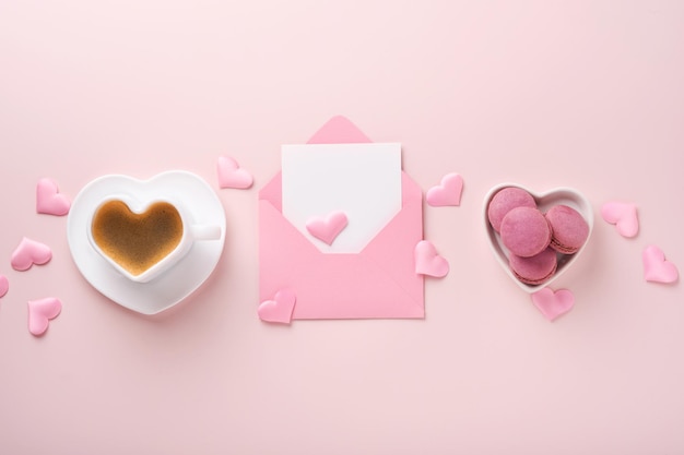 발렌타인 데이 카드입니다. 안에 빈 흰색 메모가 있는 분홍색 빈 봉투, 마카롱 마카롱 쿠키, 분홍색 배경에 하트 모양의 커피 컵. 3월 8일, 발렌타인 데이, 생일 카드. 조롱.