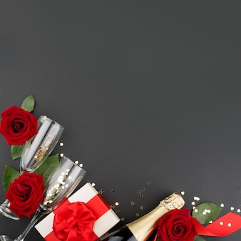 발렌타인 데이 구성 평면은 선물 상자 장미 꽃 선물 샴페인 및 텍스트 복사 공간이 있는 검은 배경에 하트 디자인 요소가 있는 평면도입니다.