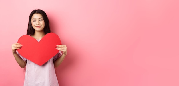 무료 사진 발렌타인 개념 r에 사랑에 빠지는 큰 붉은 마음 카드를 보여주는 귀여운 십 대 아시아 소녀