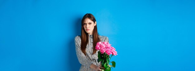 Valentines day concept displeased young woman rejecting flowers gift frowning and grimacing refusing