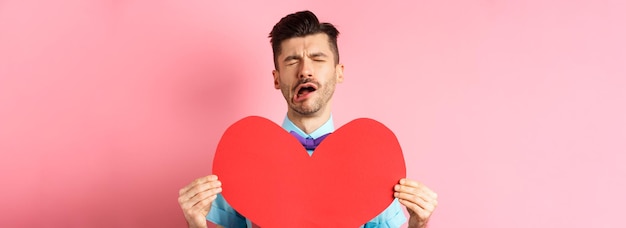 Free photo valentines day concept sad and lonely man feeling heartbroken being rejected showing big red heart c