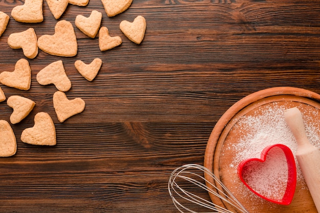 Valentines day cookies with kitchen utensils on wooden background