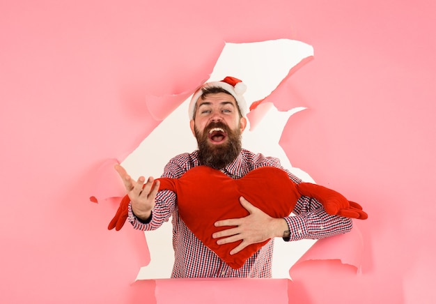 발렌타인 데이 휴일에는 하트 모양의 베개를 들고 웃는 산타 남자가 보이는 개념을 축하합니다.