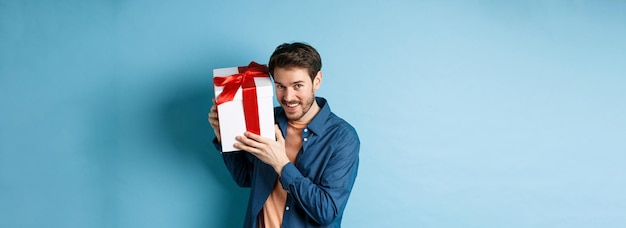 Free photo valentines day romantic boyfriend showing gift box for lover celebrating anniversary standing over b