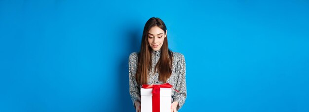 Valentines day surprised caucasian woman gasping amazed and looking at romantic gift standing on blu