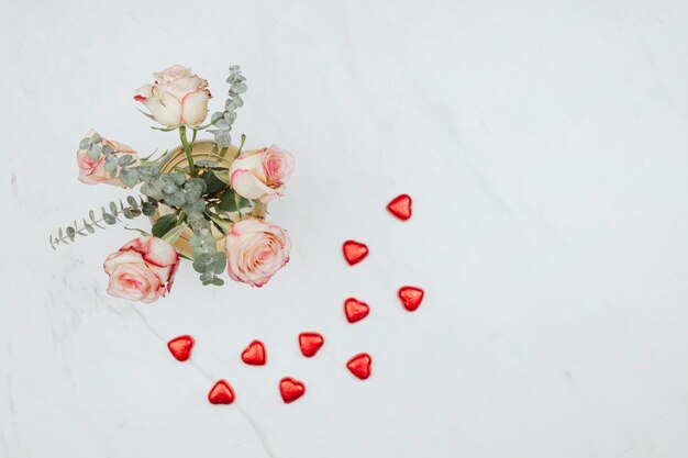 Valentines rose bouquet with red chocolate hearts on a white marble background