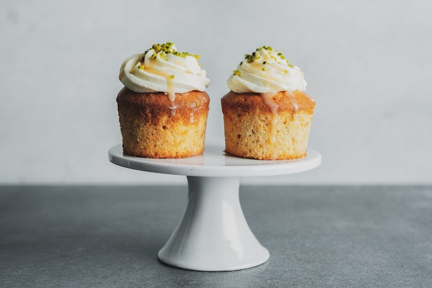 Cupcakes alla vaniglia con crema e caramello su sfondo grigio da tavola.