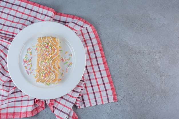 Бесплатное фото Сладкий рулет со вкусом ванили, украшенный посыпкой на белой тарелке.