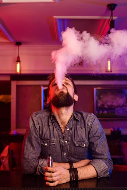 Free photo vape. vaping man in a cloud of vapor. photo is taken in a vape bar. vape shop