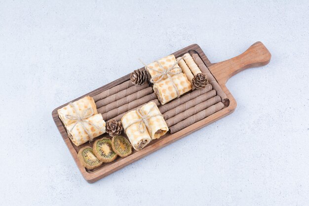 Variety of biscuits and dried kiwi on wooden board. 