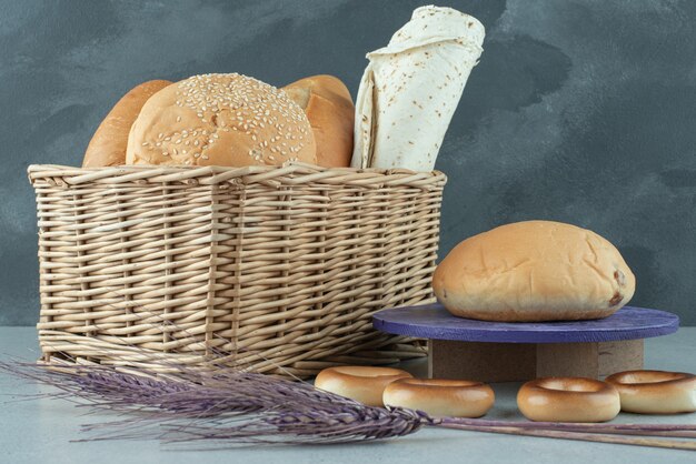 Variety of bread in basket and crackers on stone surface