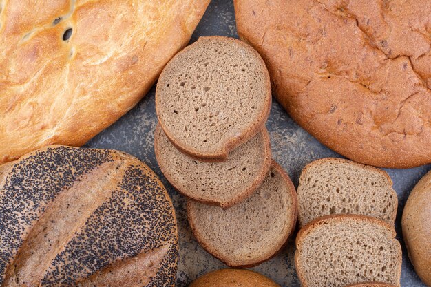 На мраморной поверхности собраны разные виды хлеба.