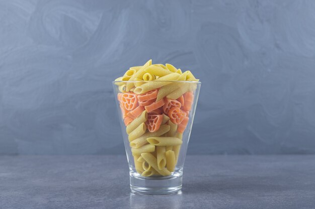 Variety of colorful raw pasta in glass.