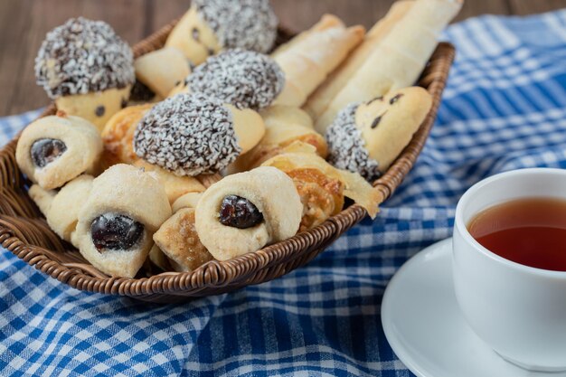 Variety of cookies in the platter with a cup of tea aside.