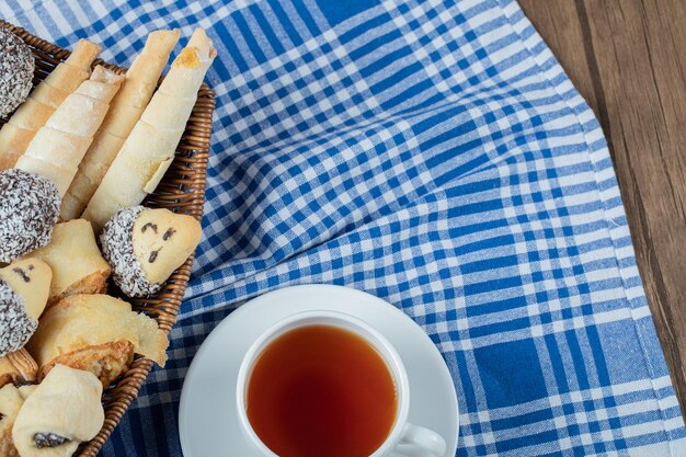 Variety of cookies in the platter with a cup of tea aside.