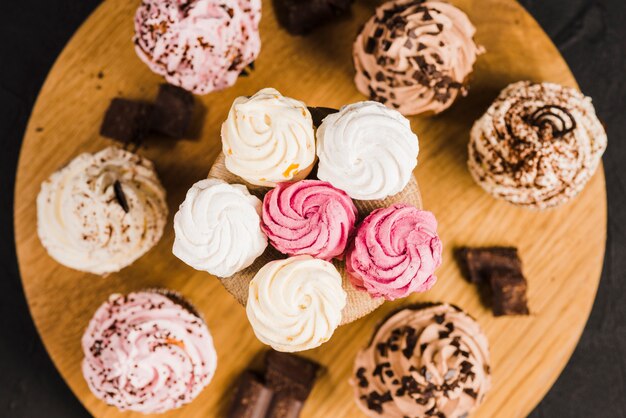 Variety of cupcakes and whipped creams on wooden cakestand