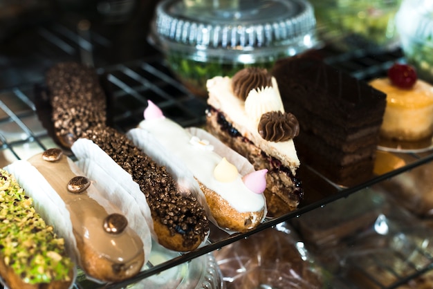 Variety of eclairs and delicious cake pastries in the display cabinet