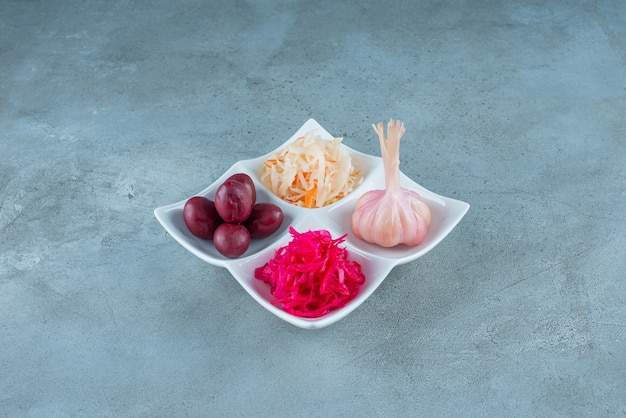 A variety fermented vegetables in a plate , on the marble table. 