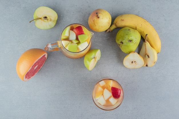 Una varietà di frutta e un bicchiere di succo sullo sfondo di marmo. foto di alta qualità