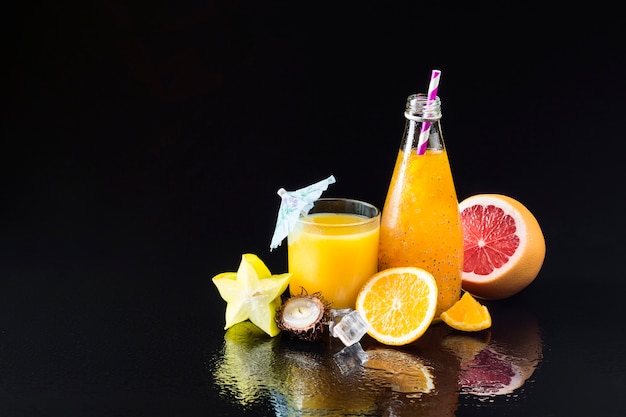 Variety of fruit and juices on black background