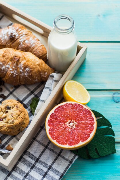 Variety of healthy breakfast in wooden tray with citrus fruits