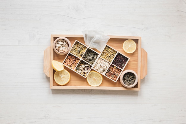 Free photo variety of herbs and dried chinese chrysanthemum flowers arranged in small container on wooden tray