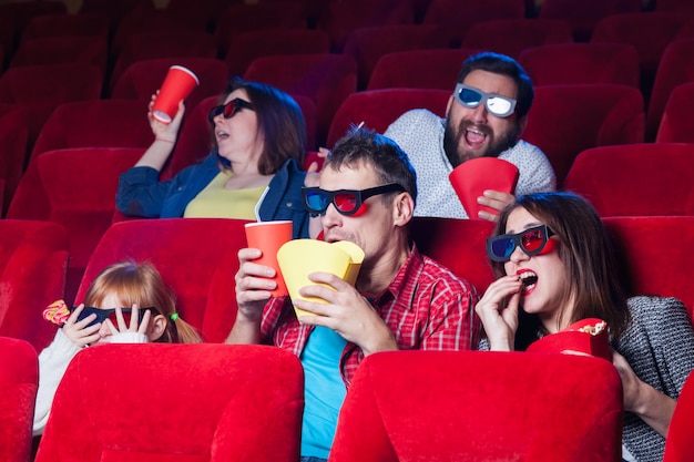 A variety of human emotions of friends holding a cola and popcorn in the cinema.